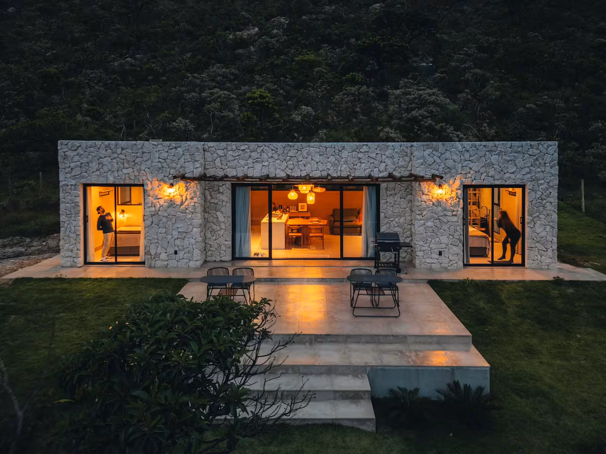 Casa alto padrão à noite com fachada em pedra e iluminação aconchegante